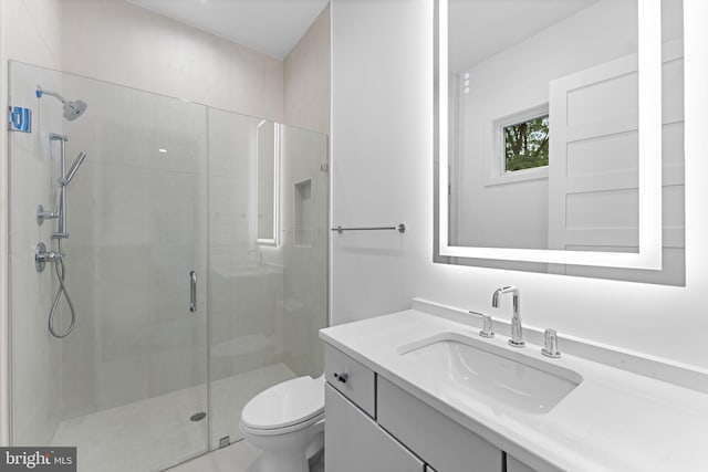 bathroom featuring a shower with door, vanity, and toilet