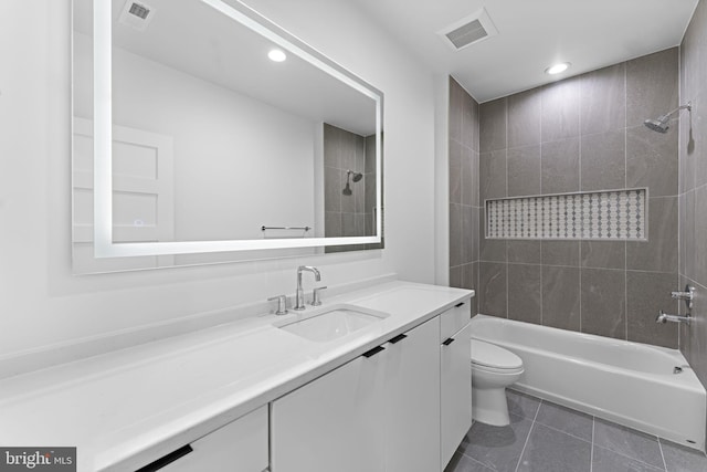 full bathroom featuring tiled shower / bath, vanity, toilet, and tile patterned flooring