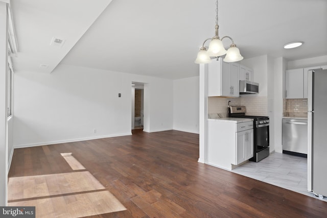 kitchen featuring appliances with stainless steel finishes, white cabinetry, pendant lighting, decorative backsplash, and light hardwood / wood-style flooring