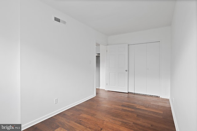 unfurnished bedroom with a closet and dark hardwood / wood-style flooring