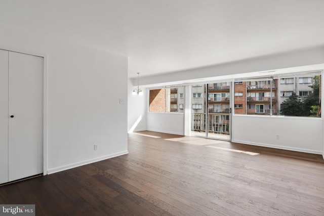 unfurnished room featuring a chandelier and dark hardwood / wood-style floors