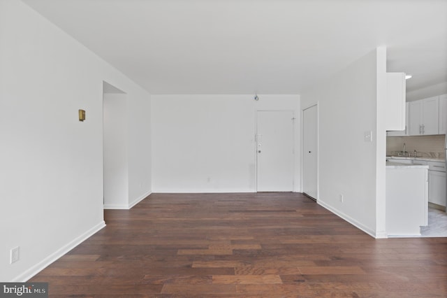 unfurnished living room with sink and dark wood-type flooring