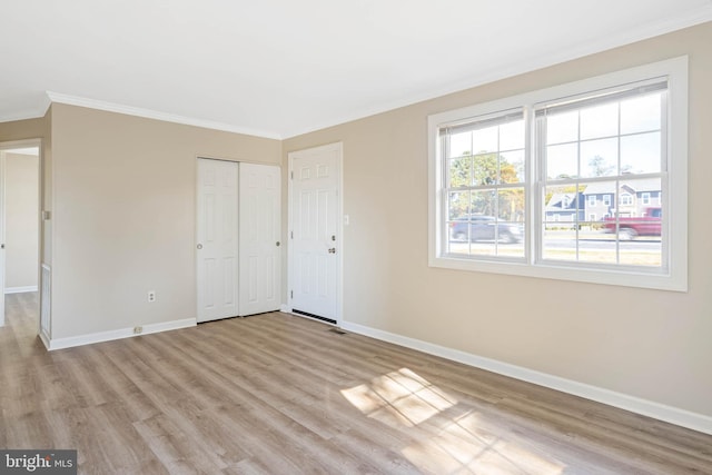 unfurnished bedroom featuring a closet, crown molding, and light wood-type flooring