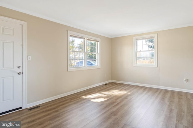 empty room featuring crown molding, light hardwood / wood-style floors, and plenty of natural light