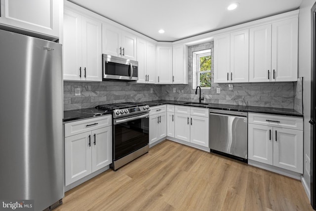 kitchen with a sink, light wood-type flooring, white cabinets, appliances with stainless steel finishes, and recessed lighting