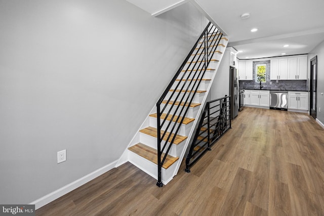 stairs featuring baseboards, wood finished floors, and recessed lighting