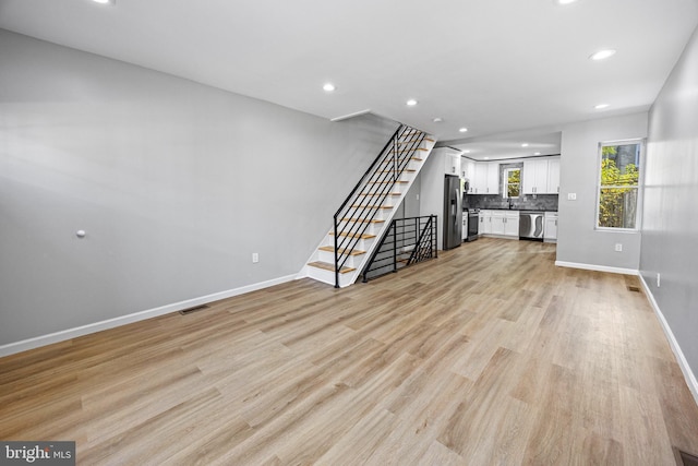 unfurnished living room featuring stairs, light wood-type flooring, baseboards, visible vents, and recessed lighting