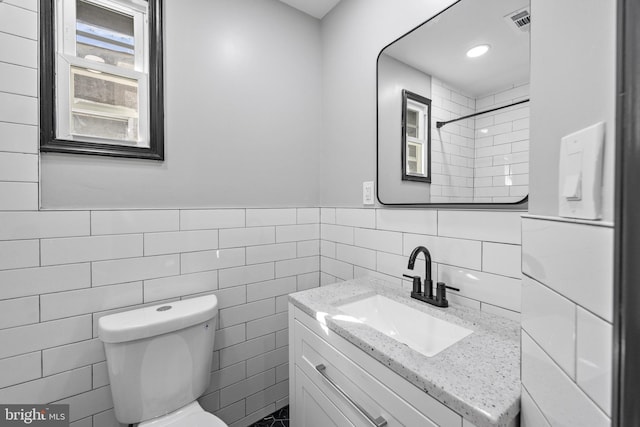 full bath featuring visible vents, toilet, vanity, tile walls, and walk in shower