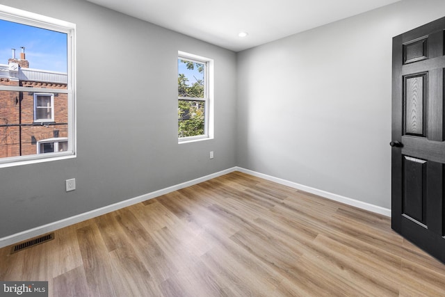 empty room featuring baseboards, wood finished floors, and visible vents