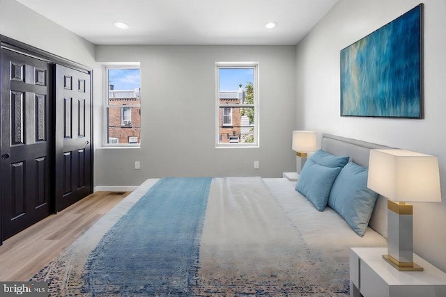 bedroom with recessed lighting, wood finished floors, and multiple windows