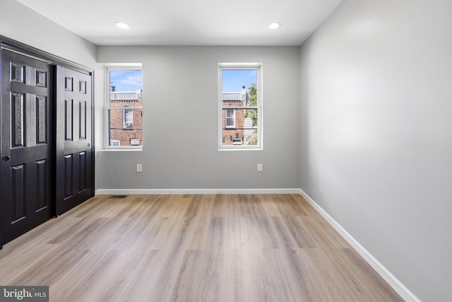unfurnished bedroom with baseboards, multiple windows, and light wood finished floors