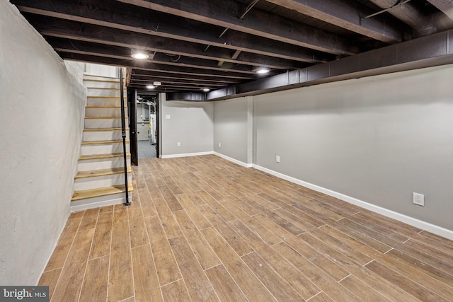 finished below grade area with baseboards, wood finished floors, and stairway