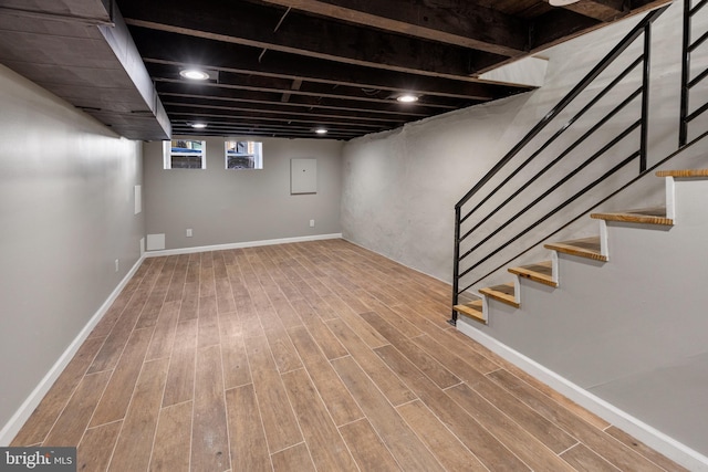 basement with wood finished floors, baseboards, and stairway