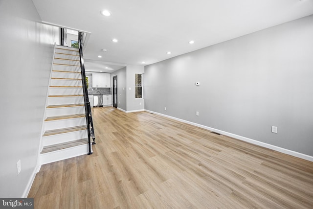 unfurnished living room with recessed lighting, baseboards, and stairs