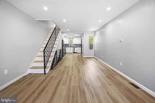 unfurnished living room featuring recessed lighting, stairs, and baseboards