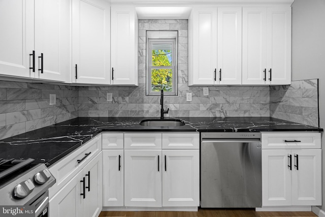kitchen featuring stainless steel appliances, a sink, white cabinetry, and tasteful backsplash