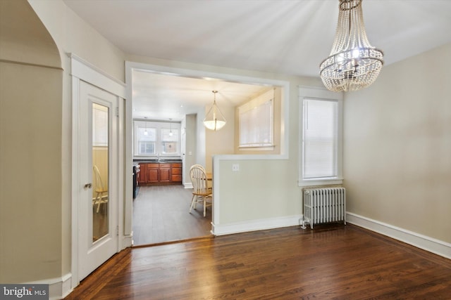 unfurnished dining area with a notable chandelier, radiator heating unit, and dark hardwood / wood-style flooring