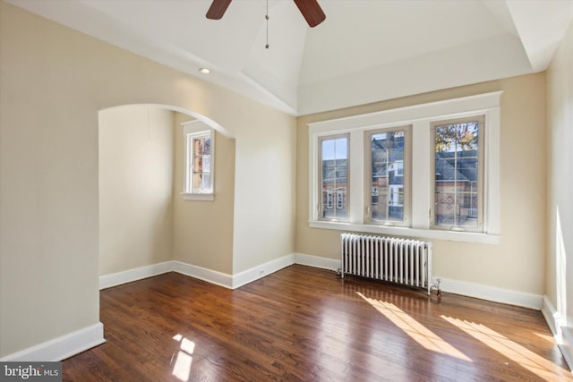 empty room featuring radiator heating unit, dark wood-type flooring, vaulted ceiling, and ceiling fan