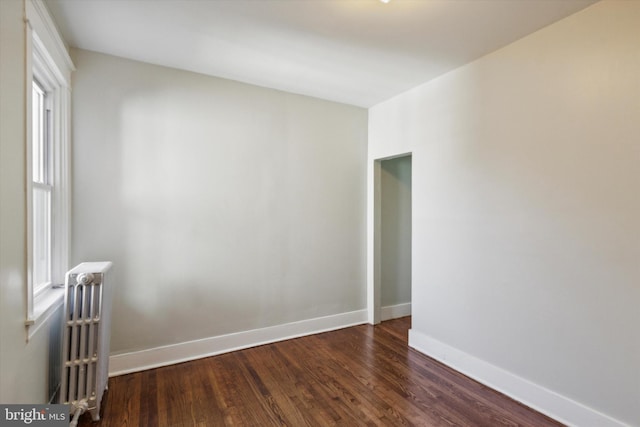 spare room with radiator heating unit and dark wood-type flooring