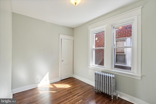 spare room with dark wood-type flooring and radiator heating unit