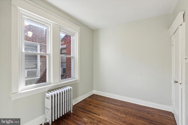 spare room featuring radiator heating unit and dark hardwood / wood-style floors