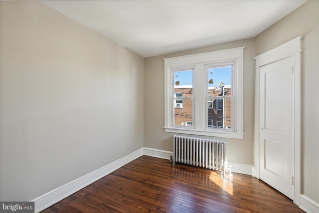 empty room featuring dark wood-type flooring and radiator heating unit