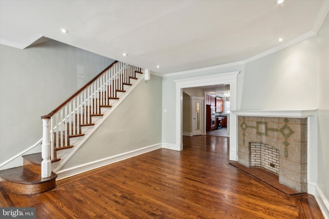 unfurnished living room with an inviting chandelier, crown molding, a tile fireplace, and dark hardwood / wood-style flooring