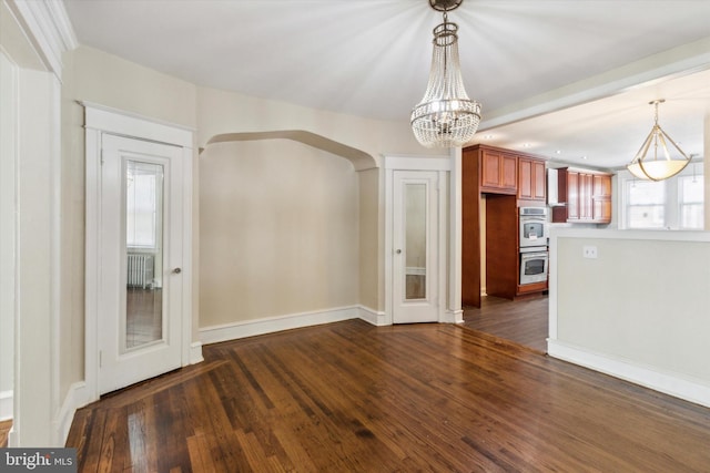 unfurnished dining area with a notable chandelier, radiator, and dark hardwood / wood-style flooring