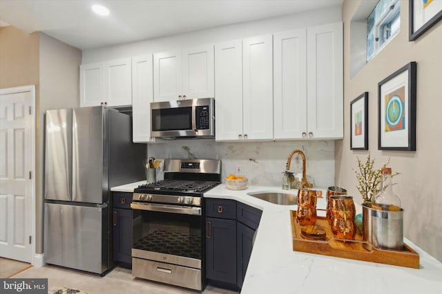 kitchen featuring decorative backsplash, sink, white cabinets, appliances with stainless steel finishes, and light stone counters