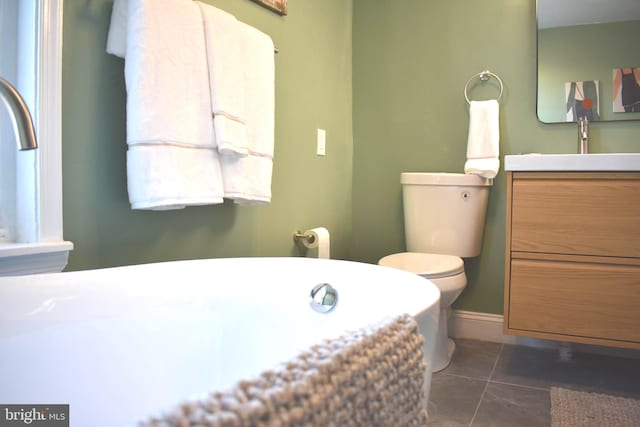 bathroom featuring vanity, toilet, tile patterned floors, and a washtub