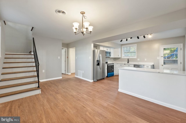 kitchen featuring hanging light fixtures, appliances with stainless steel finishes, light wood-type flooring, and white cabinets