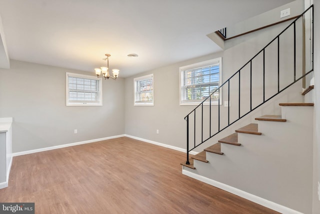 stairs with wood-type flooring and an inviting chandelier