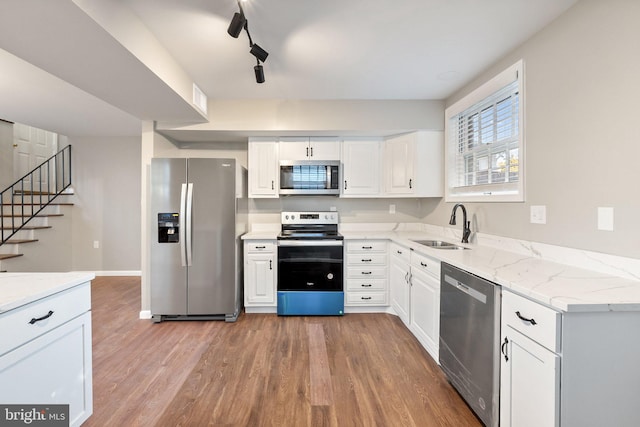 kitchen featuring appliances with stainless steel finishes, sink, wood-type flooring, rail lighting, and white cabinets