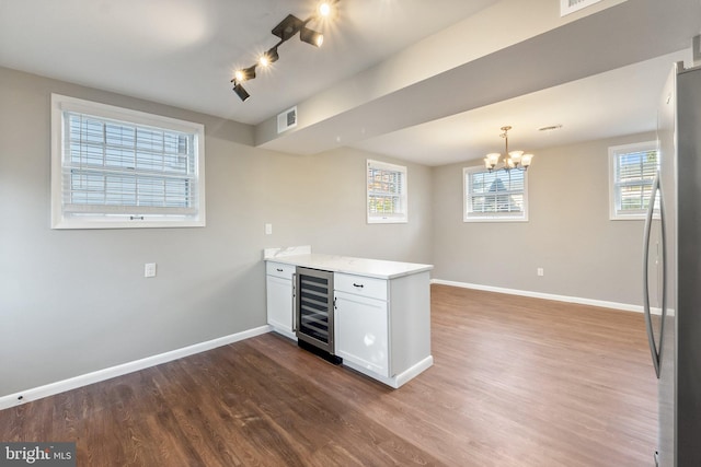 kitchen featuring wine cooler, white cabinetry, wood-type flooring, stainless steel refrigerator, and decorative light fixtures