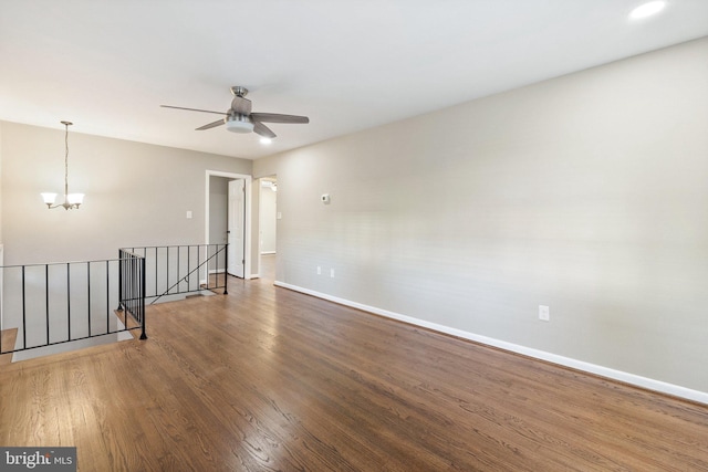 empty room with hardwood / wood-style floors and ceiling fan with notable chandelier