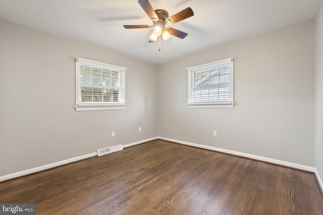 unfurnished room featuring a healthy amount of sunlight, dark wood-type flooring, and ceiling fan