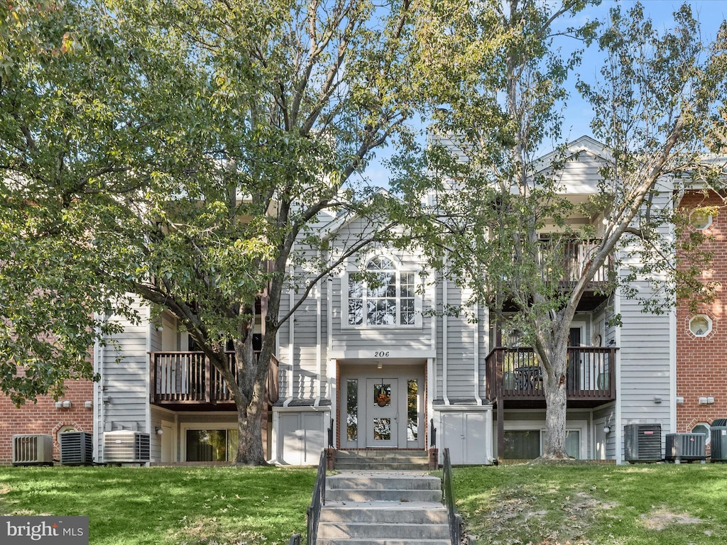 view of front of home with cooling unit, a front yard, and a balcony