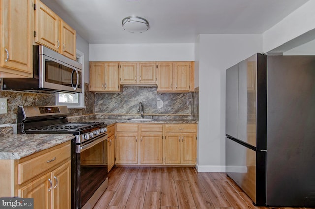 kitchen featuring tasteful backsplash, light brown cabinetry, light hardwood / wood-style flooring, sink, and stainless steel appliances