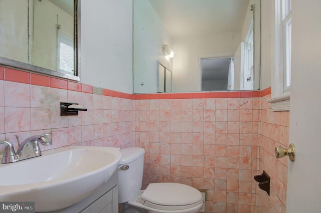 bathroom with vanity, toilet, and tile walls