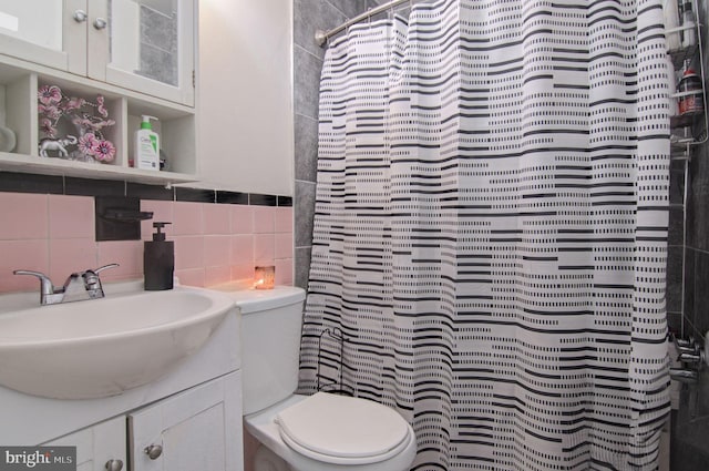 bathroom with toilet, walk in shower, tile walls, vanity, and decorative backsplash