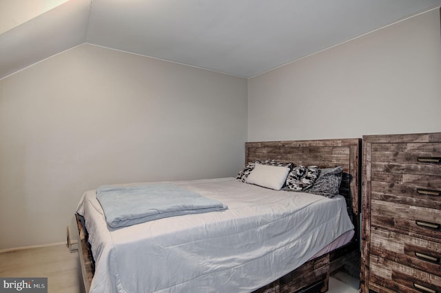 bedroom with light hardwood / wood-style floors and lofted ceiling