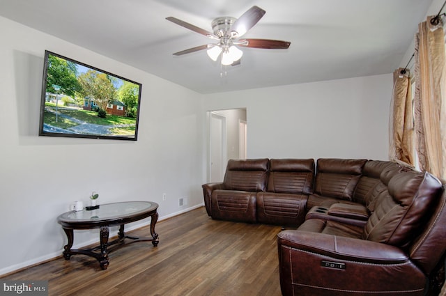 living room featuring dark wood-type flooring and ceiling fan