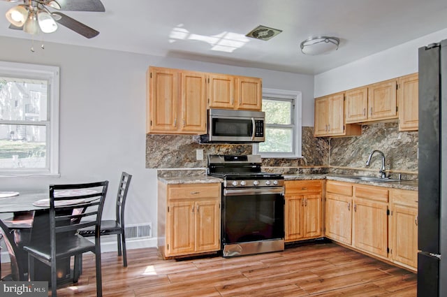 kitchen with backsplash, stainless steel appliances, sink, and light wood-type flooring