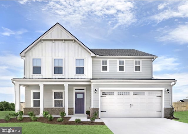 view of front of home with a front yard, covered porch, and a garage