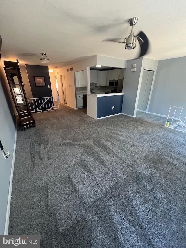 unfurnished living room with dark carpet and ceiling fan