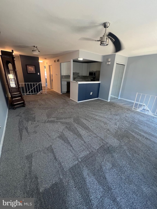 unfurnished living room featuring carpet floors and ceiling fan