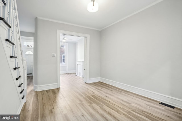 spare room featuring light wood-type flooring and crown molding