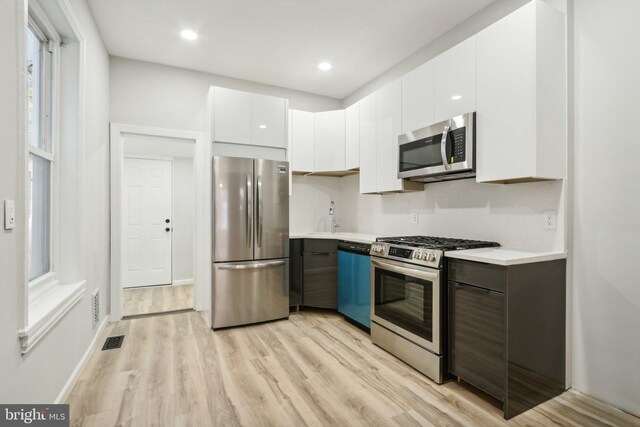 kitchen with light hardwood / wood-style floors, white cabinetry, sink, and appliances with stainless steel finishes