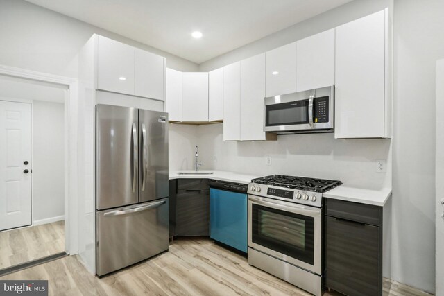 kitchen featuring stainless steel appliances, white cabinets, sink, and light hardwood / wood-style flooring