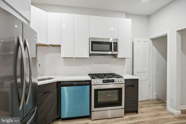 kitchen featuring white cabinetry, sink, light hardwood / wood-style floors, and stainless steel appliances